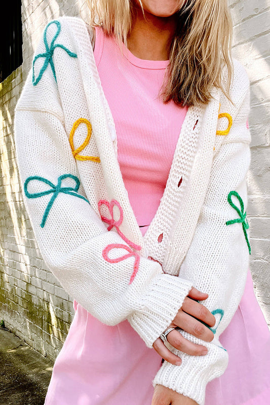 Cardigan con bottoni lavorato a maglia con spalle scoperte e fiocco bianco